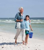 Woman and child walking on beach with FreeStyle® Comfort® Portable Oxygen Concentrator by CAIRE in carrier | Panakeia Medical Products Distributor